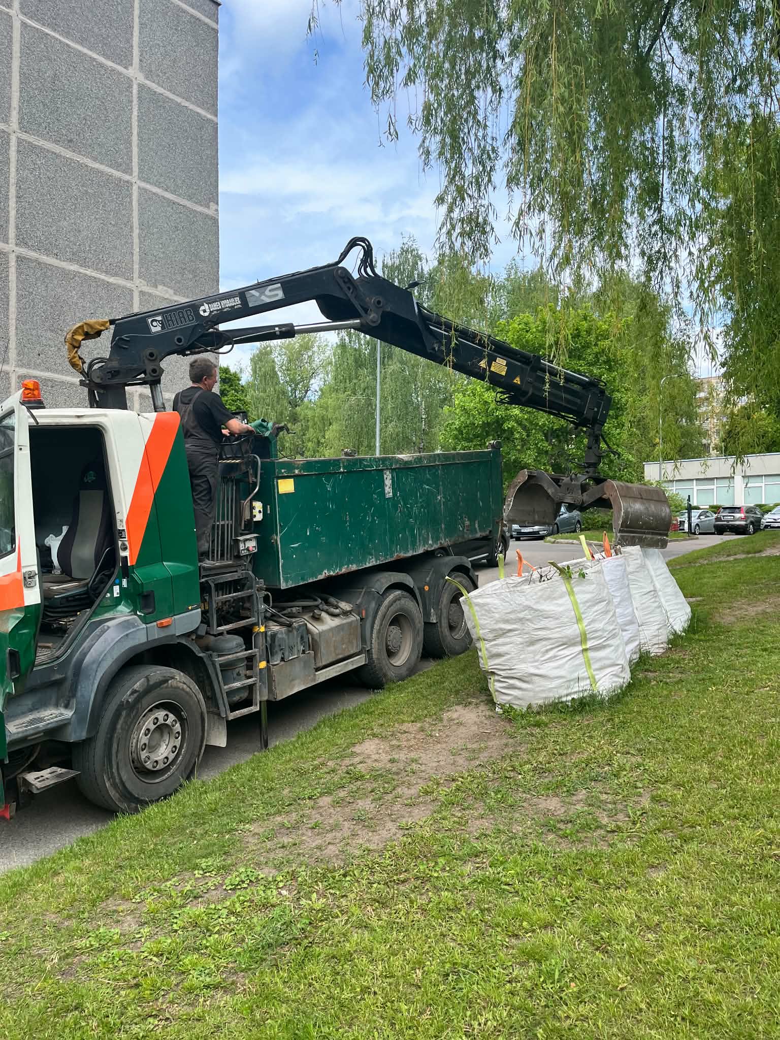 Savivartis su griebtuvu krauna atliekas prie pastato